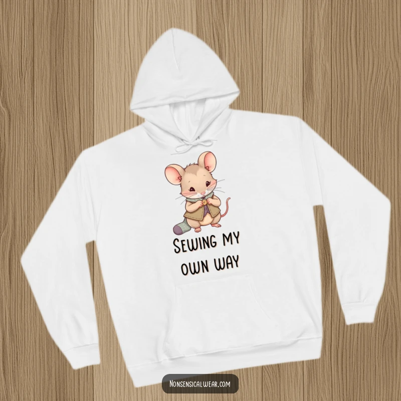 Funny Mouse Hoodie: A curious mouse in a vest is sewing a button onto a small sock, offering warmth and charm.