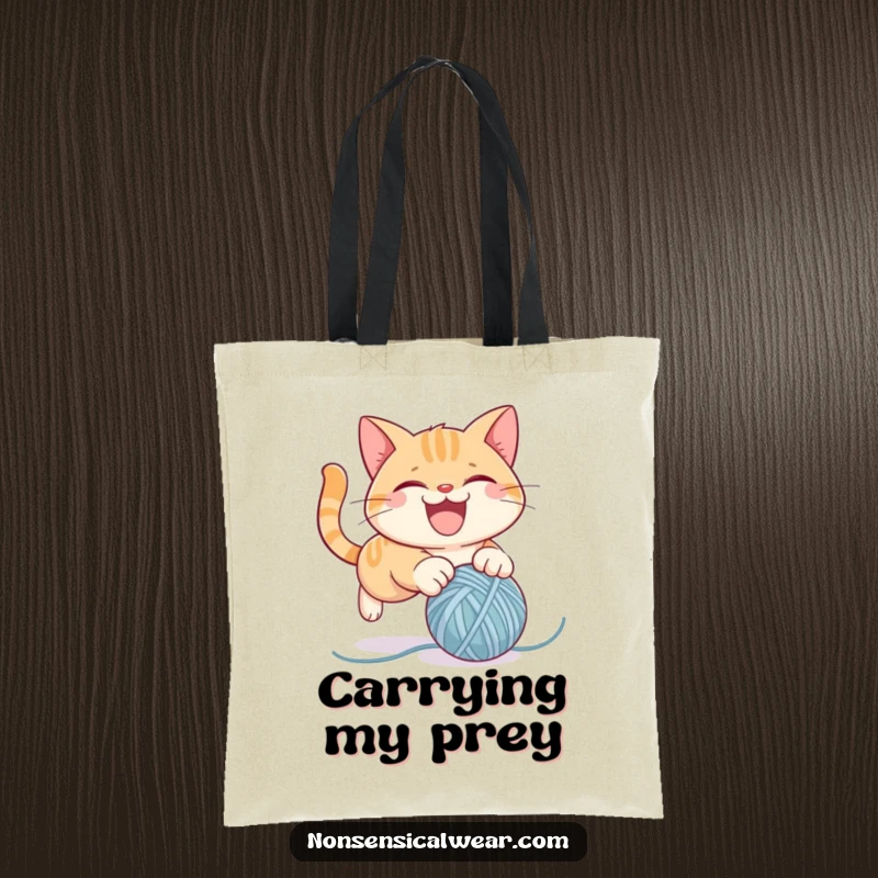 Funny tote bag featuring a mischievous cat character leaping towards a bouncing ball of yarn, combining utility and humor.