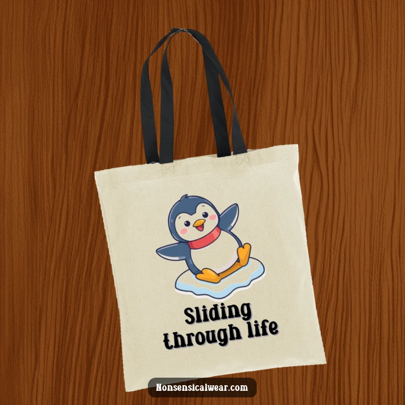 Funny tote bag featuring a happy penguin character mid-slide down an icy slope, perfect for everyday use.